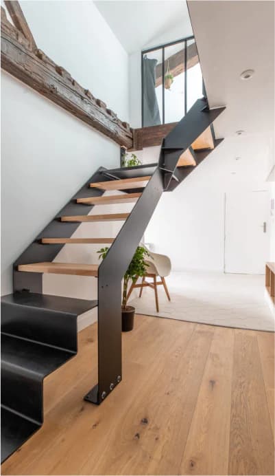 Escalier en acier noir et marches en chêne dans un intérieur lumineux